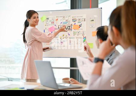 Eine zuversichtliche und attraktive asiatische Technikentwicklerin leitete das Meeting mit ihrem Team und besprach gemeinsam ein neues Projekt. Stockfoto