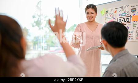 Eine professionelle asiatische Technikentwicklerin stellt ihren Kollegen ihr Projekt vor und erstellt gemeinsam ein Brainstorming zu einem neuen Projekt. Stockfoto