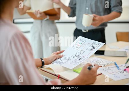 Nahaufnahme einer professionellen weiblichen UI-Entwicklerin nimmt mit ihren Kollegen an einem Meeting Teil, um eine neue mobile Anwendung zu entwickeln. Stockfoto