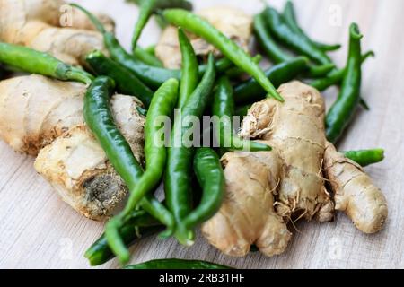 Frischer Ingwer und grüner Chili-Pfeffer auf einem einfachen Holztisch, grünes Gemüse für alle wichtigen Lebensmittel, Blick auf ungeschältes Gemüse mit Normalware Stockfoto