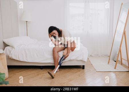 Behinderung Frau prothetische Beinkonsumenten Stress traurig weinen allein zu Hause Schlafzimmer psychische Probleme leiden Schmerzen Stockfoto