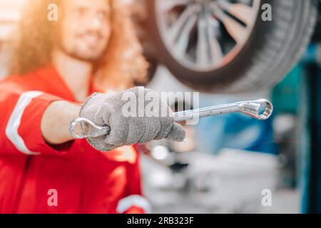 Glücklicher Mechaniker Reifenwartungsplan prüfen Auto in der Garage, Auto-Reifen-Austauschkonzept. Stockfoto