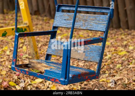 Alte Schaukel für Kinder, die im Herbst in einem Park in der ukraine in der Stadt dnipro aufgegeben wurden Stockfoto