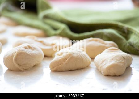 Rohe Pasteten mit Kartoffeln auf einem weißen Tisch in der Küche, hausgemachte Pasteten Stockfoto