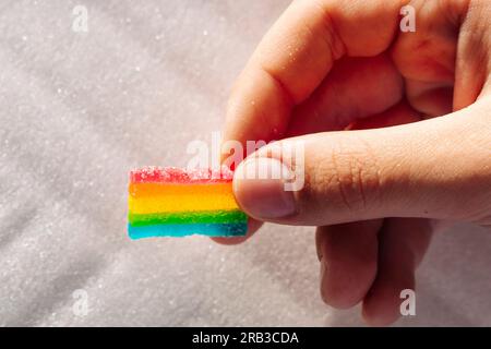 Regenbogenmarmeladen in der Kinderhand. Leckereien und Süßigkeiten. Kinderfreuden. Süße und saure Kauteller mit Zucker. Bunte Süßigkeiten, Marmal Stockfoto