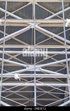 Bau eines Gebäudes unter Verwendung von Gerüsten. Renovierungsarbeiten an der Fassade. Gerüstfragment und Treppe gegen die Hauswand. Sicherheit am Konstrukt Stockfoto