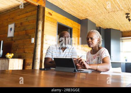 Ein hochrangiges afroamerikanisches Paar, das zu Hause Papierkram mit einem Tablet erledigt. Senioren-Lebensstil, Kommunikation, Finanzen und Ruhestand, unverändert. Stockfoto