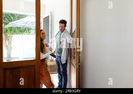 Ein glückliches, weißes Paar, das Taschen in der Hand hält, als es vom Einkaufen nach Hause kam. Lifestyle, Shopping und häusliches Leben, unverändert. Stockfoto