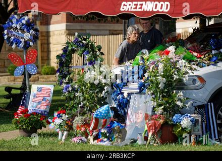 Zwei Besucher untersuchen Blumen und Gedenkfeiern, die sich am Donnerstag, den 6. Juli 2023 in der Nähe des Rathauses in Tell City, Troy Township, Perry County, IN, USA, auf und um das Patrouillenfahrzeug Dodge Durango des Polizeikommandos Sgt. Heather J. Glenn stapeln. Glenn, 47, wurde am 3. Juli erschossen, als er versuchte, einen Verdächtigen häuslicher Gewalt in einem örtlichen Krankenhaus zu verhaften. Der erste Todesfall in der Dienstzeit in der fast 165-jährigen Geschichte des Tell City Police Department und der zweite Indiana Police Officer, der in weniger als einer Woche im Dienst getötet wurde. (APEX MediaWire Foto von Billy Suratt) Stockfoto