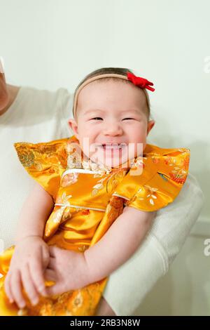 Fröhliches und lächelndes kleines Mädchen, das ein traditionelles gelbes Kleid für die Party trägt Stockfoto