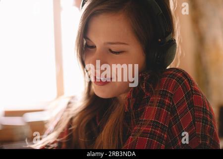 Teenager, die zu Hause Musik über Kopfhörer hört Stockfoto