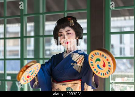 nagasaki, kyushu - 14 2022. dezember: Japanische Frau in Kimono mit furi-dutsumi-Tamburinen, geschmückt mit tomoe-Designs während einer Tanzvorführung im Stockfoto