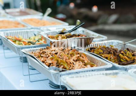 Fajitas und andere mexikanische Speisen werden im Freien auf Aluminiumtabletts serviert Stockfoto