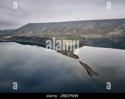 Ruhiger See umgeben von Bergen an bedeckten Tagen Stockfoto