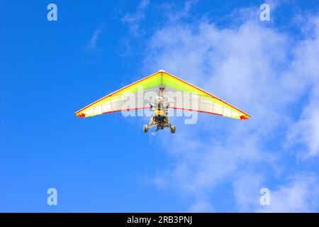 An einem klaren, sonnigen Tag fliegt ein Drachenflieger hoch am Himmel. Stockfoto