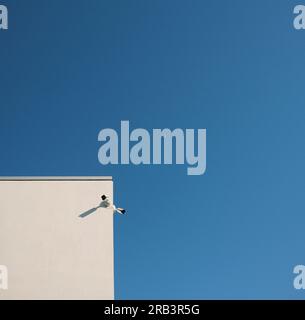 Überwachungskameras auf Gebäude gegen blauen Himmel Stockfoto