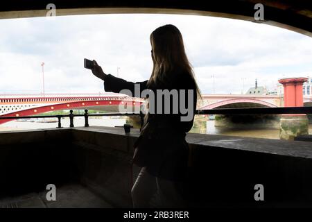 London, Großbritannien. Eine Frau, die ein Selfie unter der Blackfriars Railway Bridge am South Bank macht Stockfoto