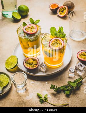 Zwei Mojito-Cocktails mit Passionsfrucht auf dem Tablett mit Limette und Minze. Stockfoto