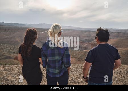 Drei Leute schauen vom Aussichtspunkt aus auf den Grand Canyon, windig Stockfoto