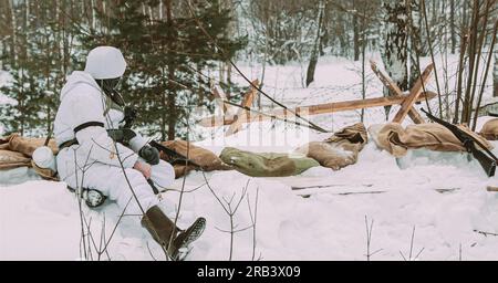 Deutscher Wehrmachts-Infanterie-Soldat im Zweiten Weltkrieg Soldaten sitzen in Hinterhalt im Winterwald. Historische Reenactment. 2. WELTKRIEG. Winter Snowy Day. Schwarz Stockfoto
