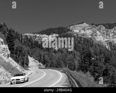 Touristen, die ein Ford Mustang Cabriolet auf dem Highway 14 Utah auf dem Weg nach Cedar fahren, brechen das Nationaldenkmal Stockfoto