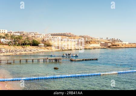 Luxuriöser Strand vor dem Hintergrund der Schönheit des Meeres mit Korallenriffen. Schöner Strand mit Liegen, strohgedeckten Sonnenschirmen und Palmen. Stockfoto