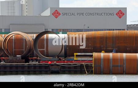 Rostock, Deutschland. 07. Juli 2023. Große Fundamente für Windturbinen des Rohrherstellers Special Pipe Construction EEW befinden sich im Überseehafen Rostock. Auf einer Presseveranstaltung am 07.07.2023 in Rostock Port werden die Halbjahresergebnisse vorgestellt. In den ersten sechs Monaten dieses Jahres passierten 15,8 Millionen Tonnen Güter am Kai im Überseehafen von Rostock. Dies ist ein Anstieg von zehn Prozent im Vergleich zum Vorjahr. Die Zahl der beförderten Fährpassagiere stieg um fünf Prozent auf eine Million. Kredit: Bernd Wüstneck/dpa/Alamy Live News Stockfoto