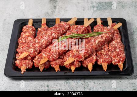 Adana Kebab. Türkisches rohes adana-Kebab auf grauem Hintergrund. Türkische Köstlichkeiten Stockfoto