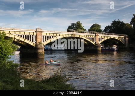 Zwei Männer paddeln in Kajaks unter der Richmond Railway Bridge auf der Themse, London, England, Großbritannien Stockfoto