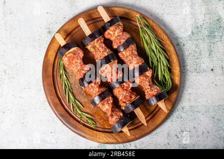 Auberginen-Kebab. Auberginen-Shish-Kebab mit rohem Hackfleisch auf grauem Hintergrund. Türkische Köstlichkeiten. Lokaler Name: Patlican Kebabi. Draufsicht Stockfoto