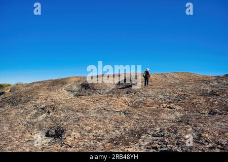 Einsame Wanderer auf stark erodiertem Flechten-bedecktem Granit im westaustralischen Outback Stockfoto