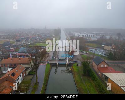 Rijkevorsel, Belgien, 23. Februar 2023, kleines Dorf Sint Jozef, auf dem Kanal Dessel Schoten Luftfoto bei Morgennebel in Rijkevorsel, kempen, Belgien, mit den Häusern und Straßen des Dorfes rund um den Kanal, Zugbrücke und Schleuse in der natürlichen grünen Landschaftslandschaft. Hochwertiges Foto. Hochwertiges Foto Stockfoto