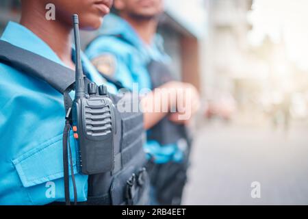 Radio, Polizei und Überwachung mit einer schwarzen Polizistin, die draußen auf Patrouille in der Stadt steht. Walkie-Talkie, Dispatch oder Kommunikation mit Stockfoto