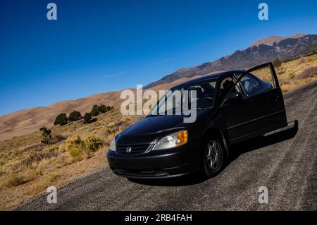 Roadtrip und Auto-Camping in einem schwarzen Honda Civic aus dem Jahr 2002 im Great Sand Dunes National Park in Colorado, USA Stockfoto