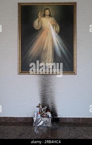 Ein Gemälde des barmherzigen Jesu mit Kerzen und religiösen Objekten Stockfoto