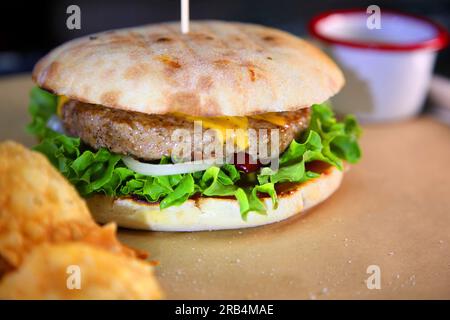 Burger mit Fleisch und Gemüse. Heißer Burger in einer brennenden Sauce. Stockfoto