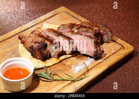 Mittelgeröstetes Steak, auf einem Holzbrett in Stücke geschnitten. Stockfoto