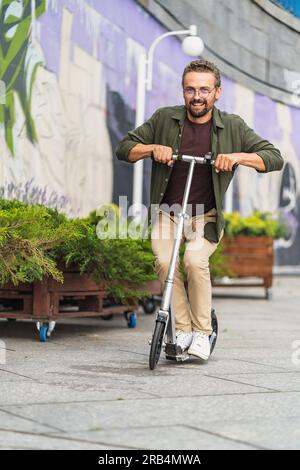 Ein Mann auf einem Roller, der Stunts mit einem großen Roller vorführt. Mit seinem attraktiven und selbstbewussten Erscheinungsbild zeigt er seine Fähigkeiten und hat eine tolle Zeit, während er sich aufregenden Manövern widmet. Hochwertiges Foto Stockfoto