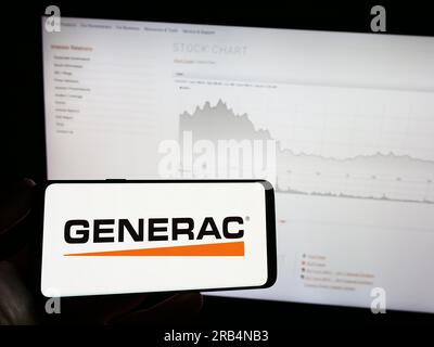 Person, die ein Mobiltelefon mit dem Logo des amerikanischen Unternehmens Generac Holdings Inc. Auf dem Bildschirm vor der Unternehmenswebseite hält. Konzentrieren Sie sich auf das Display des Telefons. Stockfoto