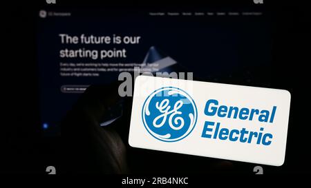 Person, die ein Smartphone mit dem Logo des US-Konglomerats General Electric Company (GE) auf dem Bildschirm vor der Website hält. Konzentrieren Sie sich auf das Display des Telefons. Stockfoto