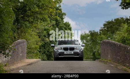 Milton Keynes, UK - Juli 6. 2023: 2011 BMW X1 auf einer schmalen Buckelbrücke Stockfoto