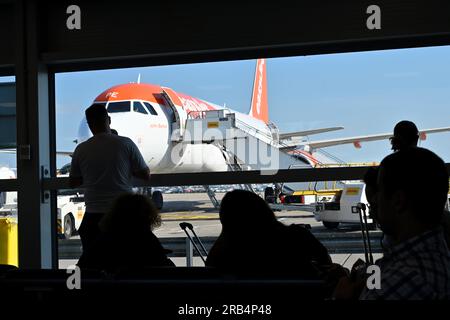 Einstiegsbereich am Flughafen mit Passagieren in Silhouette, die auf den Flug mit Blick auf das Fenster draußen warten Stockfoto