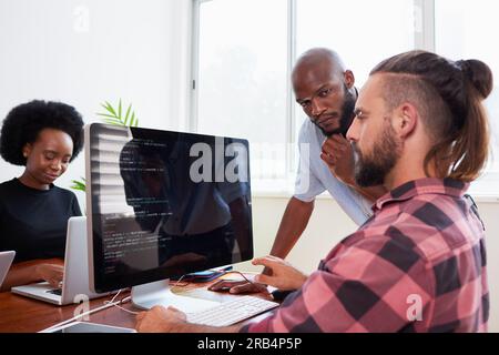 Zwei Entwickler programmieren gemeinsam im Büro, um Peer Reviews zu unterstützen Stockfoto