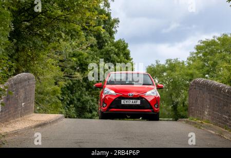 Milton Keynes, Großbritannien - 6. 2023. Juli: 2017 roter TOYOTA YARIS-Wagen auf einer schmalen Buckelbrücke Stockfoto