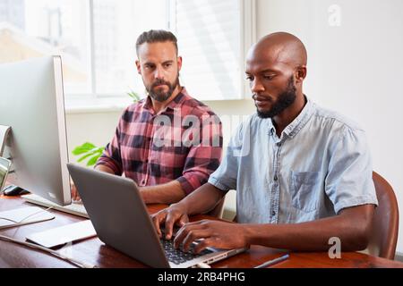 Zwei Entwickler programmieren gemeinsam im Büro und kodieren nebeneinander Stockfoto