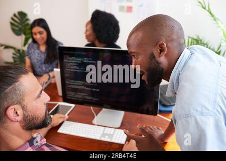 Zwei Entwickler programmieren gemeinsam im Büro, um Peer Reviews zu unterstützen Stockfoto