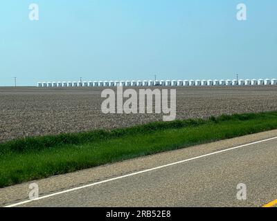 Kreml, MT, USA - 19. Mai 2023: Viele Getreidesilos stehen auf dem Highway 2 neben einer Straße in der Nähe des Kremls, Montana, in Schlange. Stockfoto