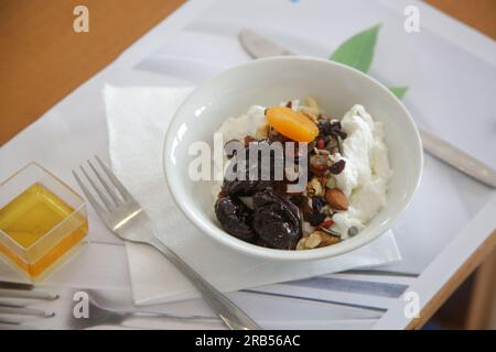 Griechischer Joghurt in Schüssel mit Honig, Nüssen, Samen und getrockneten Früchten, gesunde Frühstücksdiät Stockfoto