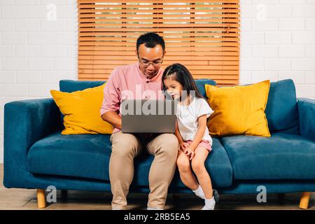 Vater, der mit dem Laptop im Wohnzimmer mit seiner Tochter spielt Stockfoto