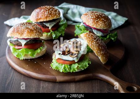 Vier portobello Pilzburger auf einem Holzteller, fertig zum Essen. Stockfoto